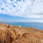 man standing on a cliff overlooking the dead sea