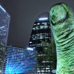 downtown paris with high-tech buildings and a statue of a big human finger
