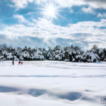 people play in the snow with sun shinging above