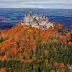 huge fairytale castle on top of a mountain surrounded by colorful trees