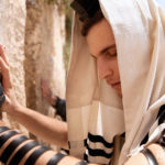 Praying man wearing tefillin at the Western Wall jerusalem