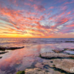 pink clouds reflected in the sea water during sunset