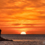fisherman in the sea on the background of the sun setting down