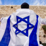 jewish worshiper wearing Israeli flag at Western Wall jerusalem