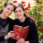 two girls holding a prayer book looking to the camera